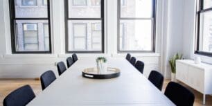 Tomt konferensrum med långt vitt bord och svarta stolar framför stora fönster, symbol för förhandling mellan arbetsgivare och fack