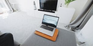 Bärbar dator på en pall i ett ljust vardagsrum, symbol för administration som sköts digitalt hemifrån